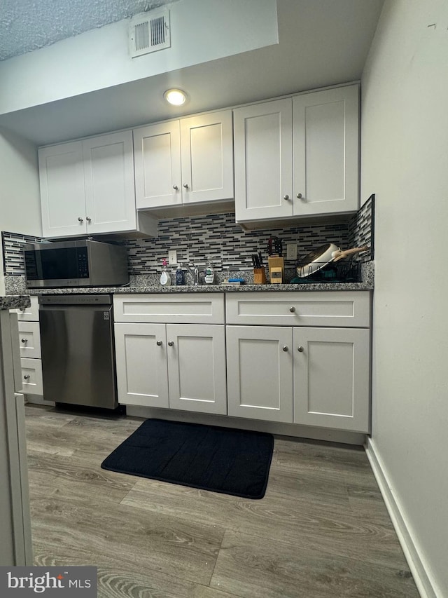 kitchen with backsplash, light hardwood / wood-style floors, white cabinetry, and stainless steel appliances