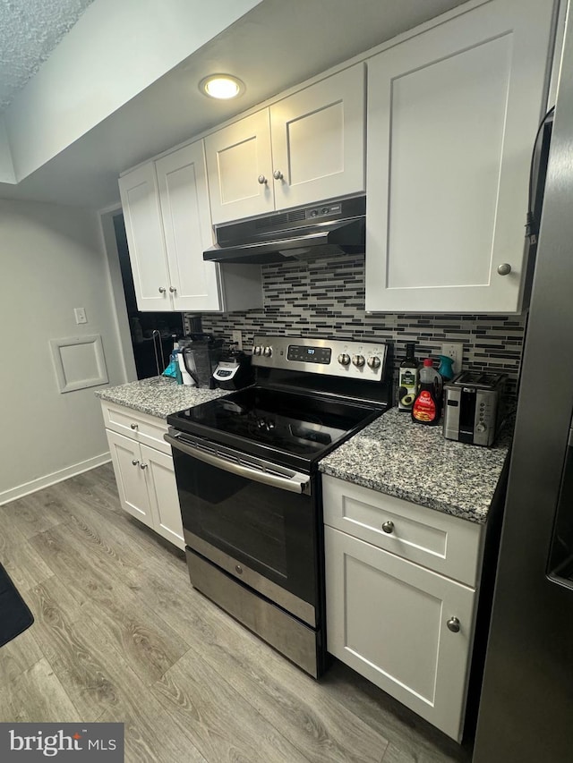 kitchen featuring light hardwood / wood-style flooring, decorative backsplash, light stone countertops, appliances with stainless steel finishes, and white cabinetry