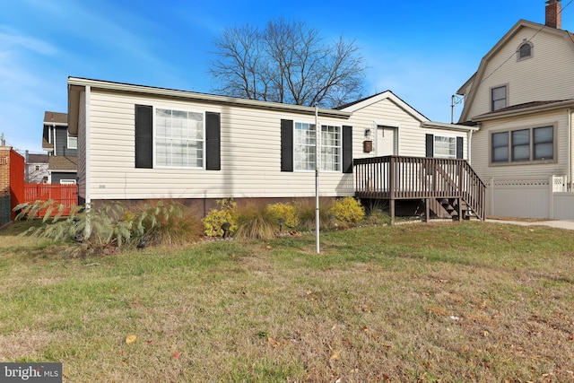 rear view of property with a wooden deck and a lawn