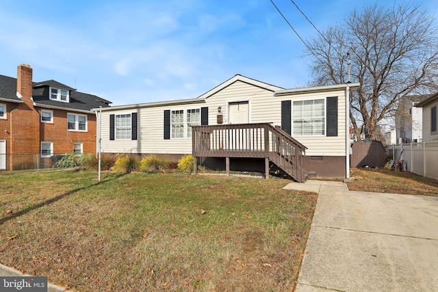 view of front facade featuring a shed, a front yard, and a deck