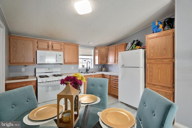 kitchen with sink, white appliances, a textured ceiling, and vaulted ceiling