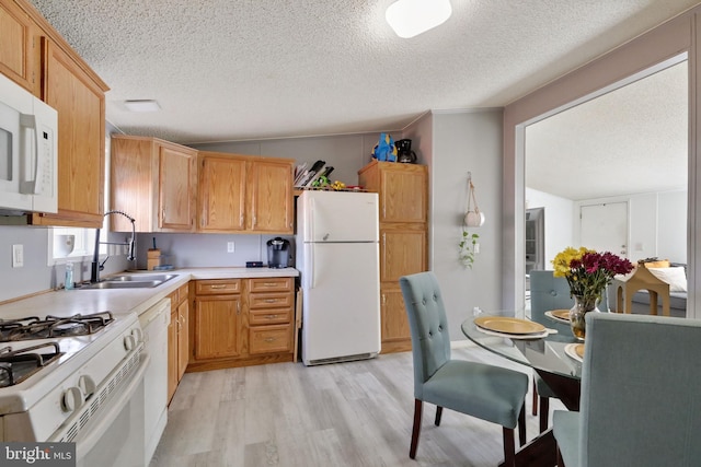 kitchen featuring lofted ceiling, white appliances, sink, light hardwood / wood-style flooring, and a textured ceiling