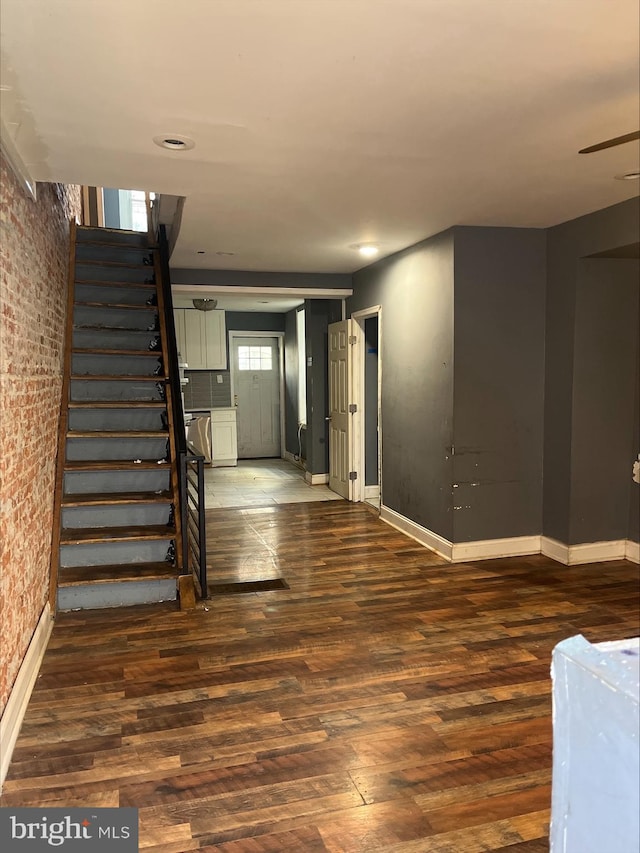 entrance foyer with dark hardwood / wood-style flooring and brick wall