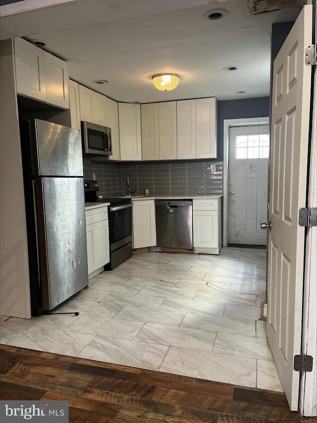 kitchen with white cabinets, backsplash, and stainless steel appliances