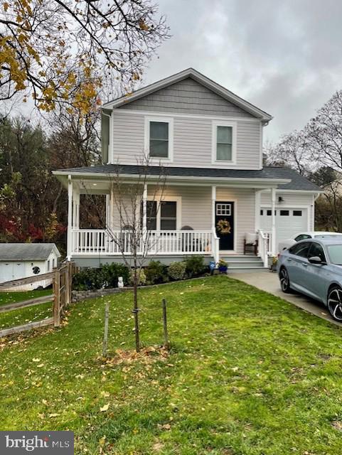 view of front of property featuring a front yard, a porch, and a garage