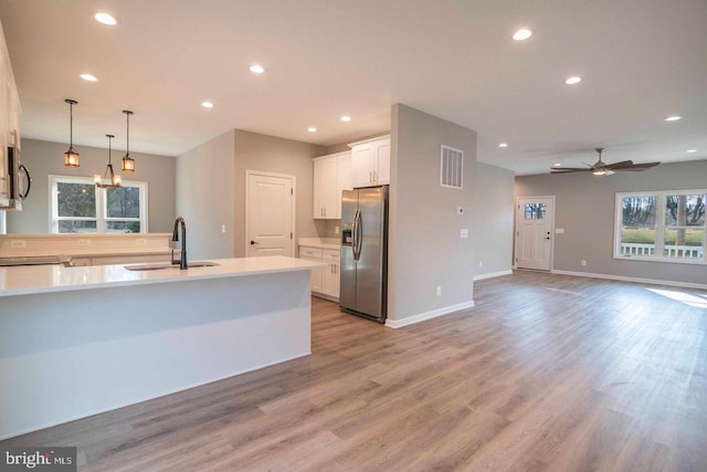 kitchen featuring white cabinets, hanging light fixtures, sink, appliances with stainless steel finishes, and light hardwood / wood-style floors