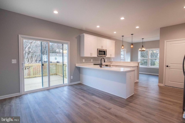 kitchen featuring plenty of natural light, sink, kitchen peninsula, and hanging light fixtures