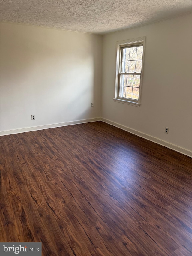 empty room featuring a textured ceiling and dark wood-type flooring