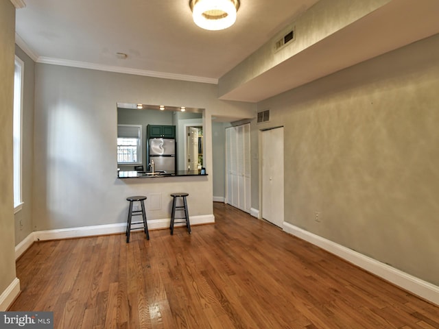 unfurnished room with hardwood / wood-style flooring, crown molding, and sink