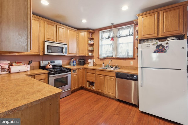 kitchen featuring hanging light fixtures, sink, light hardwood / wood-style floors, and appliances with stainless steel finishes