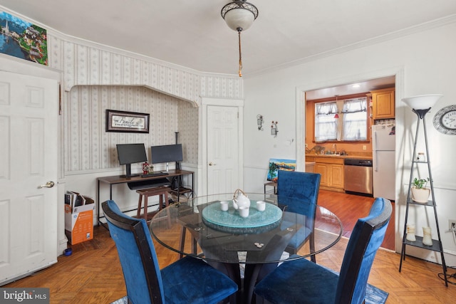 dining area featuring sink, crown molding, and light parquet floors