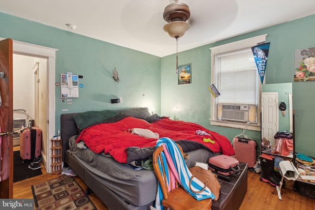 bedroom featuring hardwood / wood-style floors, ceiling fan, and cooling unit