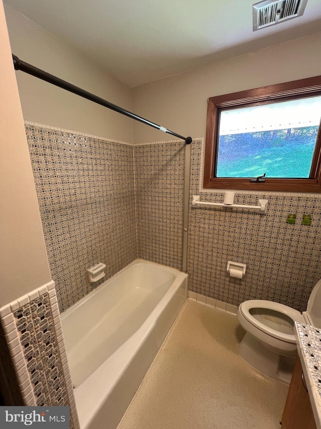 bathroom featuring shower / washtub combination, tile walls, and toilet