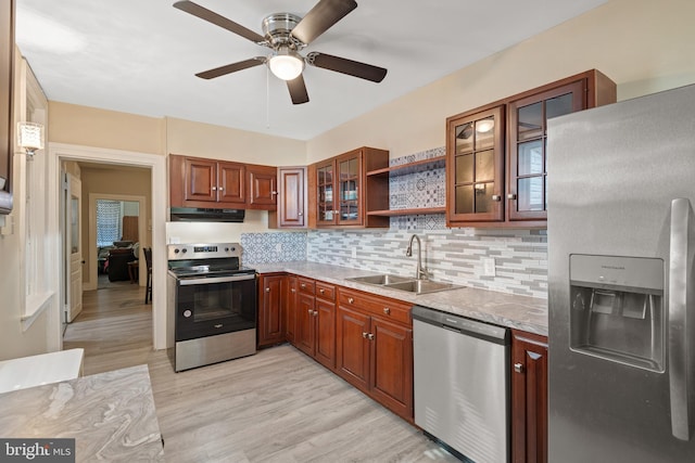 kitchen with sink, decorative backsplash, ceiling fan, light wood-type flooring, and stainless steel appliances