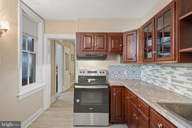 kitchen with backsplash, sink, electric range, light hardwood / wood-style floors, and light stone counters