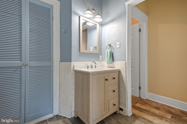 bathroom with hardwood / wood-style flooring, vanity, and tile walls