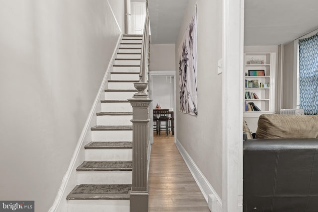 staircase with hardwood / wood-style floors and built in features