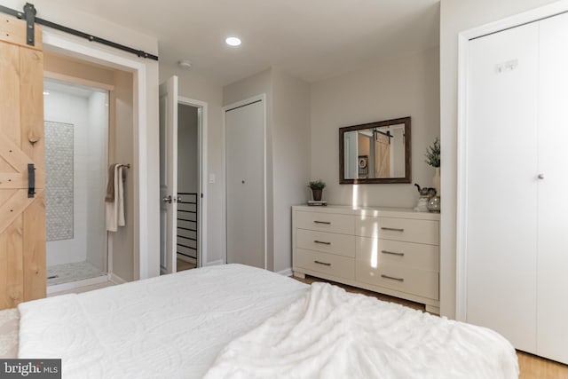 bedroom with a barn door and light wood-type flooring