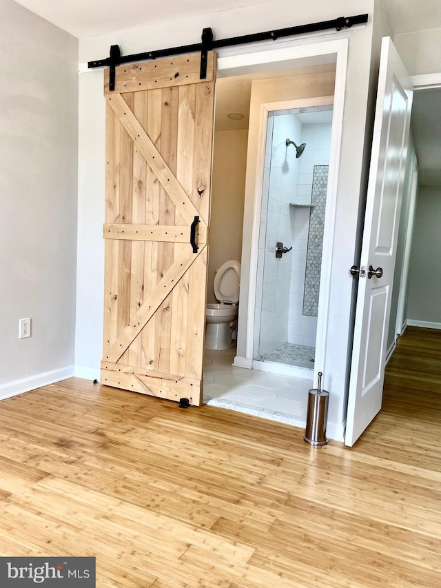 bathroom featuring tiled shower, hardwood / wood-style floors, and toilet