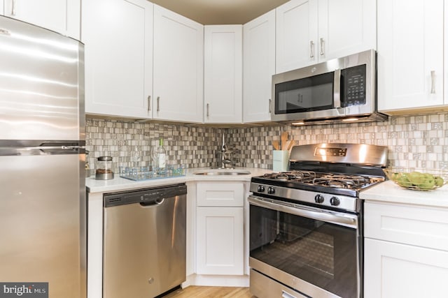 kitchen featuring decorative backsplash, white cabinets, and appliances with stainless steel finishes