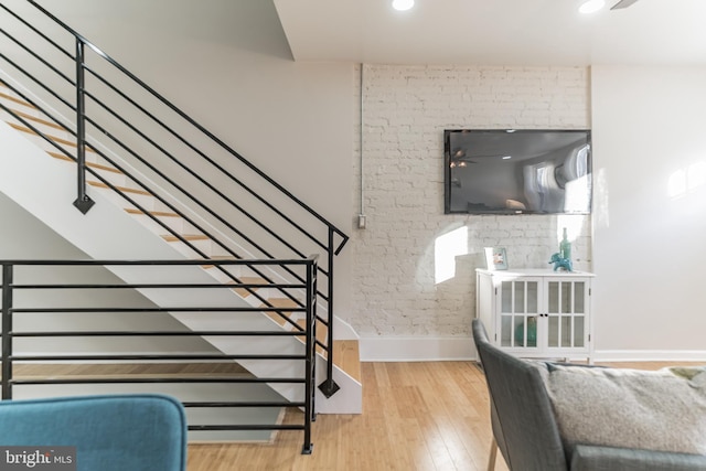 staircase featuring hardwood / wood-style floors and brick wall