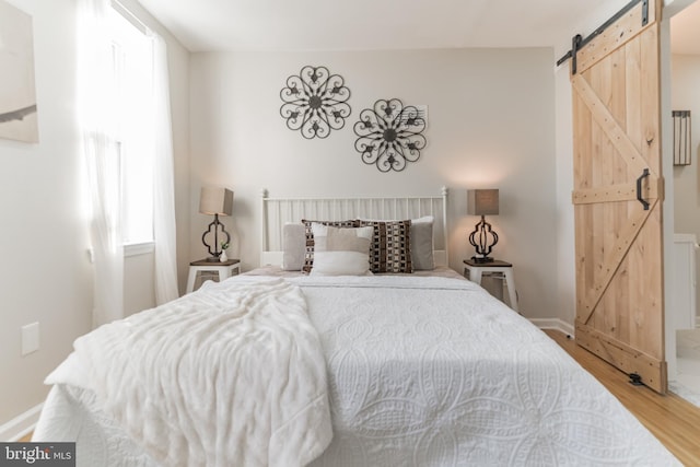 bedroom with hardwood / wood-style floors and a barn door