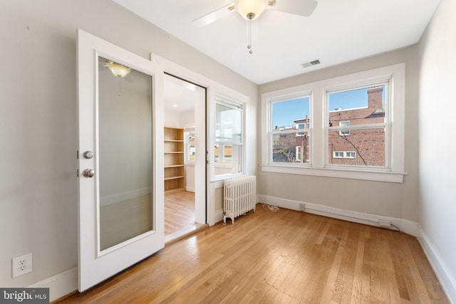 unfurnished bedroom with a closet, radiator, ceiling fan, and light hardwood / wood-style flooring