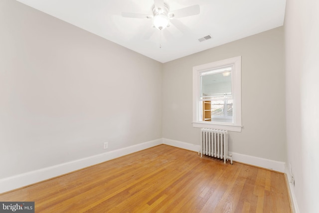 empty room with radiator heating unit, ceiling fan, and wood-type flooring