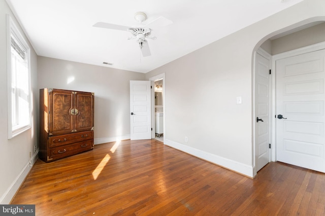 unfurnished bedroom featuring multiple windows, dark wood-type flooring, and ceiling fan