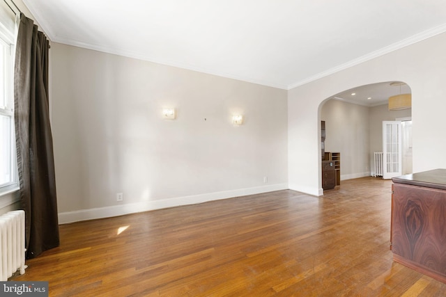 empty room featuring crown molding, radiator heating unit, and hardwood / wood-style flooring