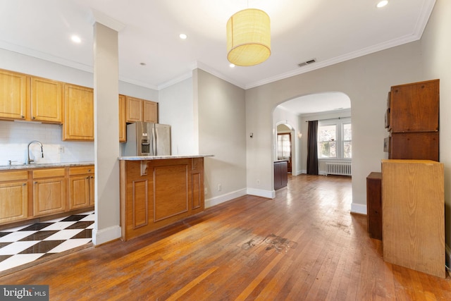 kitchen with stainless steel refrigerator with ice dispenser, backsplash, radiator, sink, and dark hardwood / wood-style floors