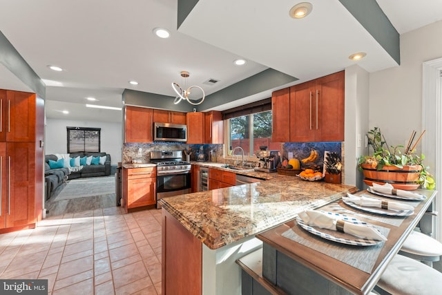 kitchen featuring a breakfast bar, backsplash, light stone counters, kitchen peninsula, and stainless steel appliances