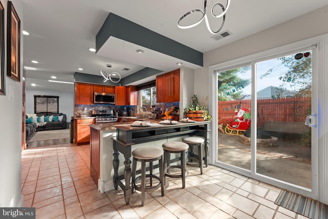 kitchen with plenty of natural light, a kitchen breakfast bar, backsplash, and appliances with stainless steel finishes