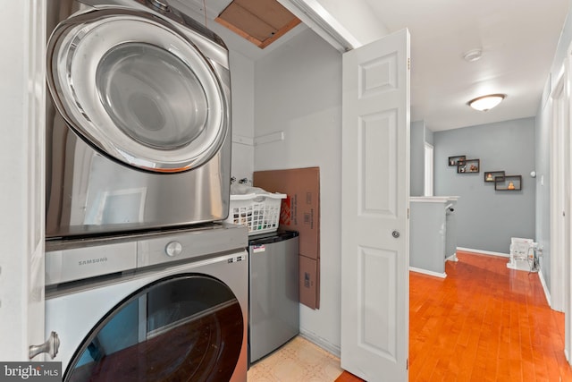 washroom with light hardwood / wood-style floors and stacked washing maching and dryer