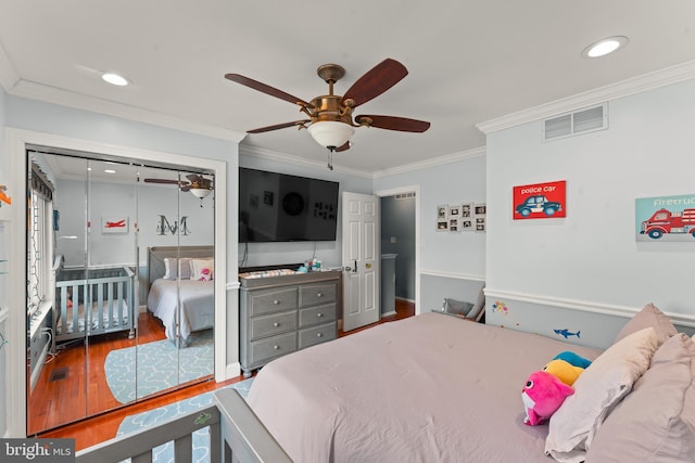 bedroom with hardwood / wood-style flooring, ceiling fan, ornamental molding, and a closet