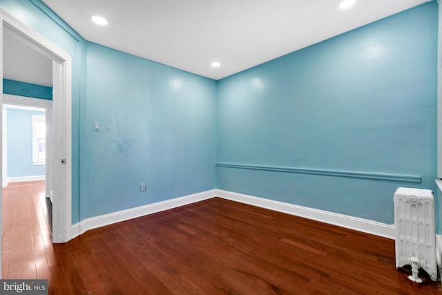 unfurnished room featuring wood-type flooring and radiator heating unit