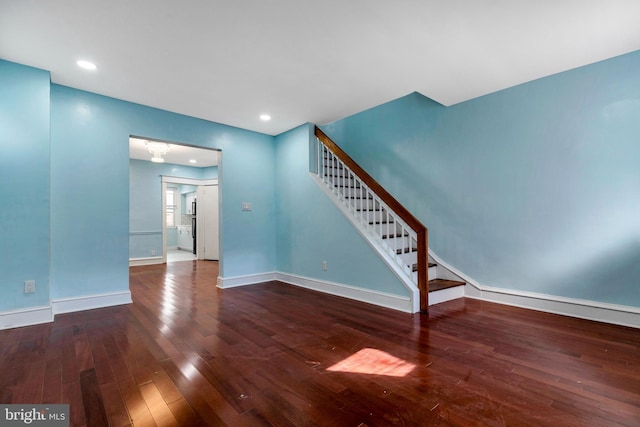 unfurnished living room with dark hardwood / wood-style floors and an inviting chandelier