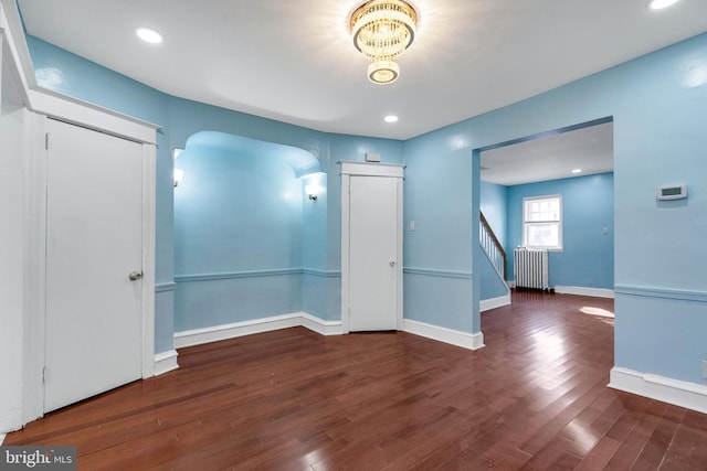 unfurnished room featuring dark hardwood / wood-style flooring and radiator heating unit