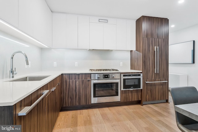 kitchen featuring light hardwood / wood-style flooring, stainless steel appliances, white cabinetry, and sink