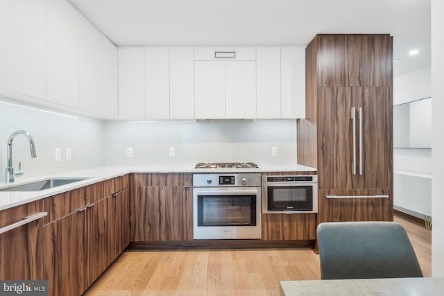 kitchen featuring light hardwood / wood-style floors, white cabinetry, sink, and appliances with stainless steel finishes