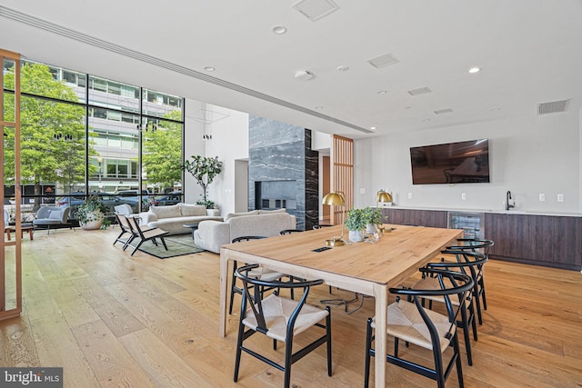 dining space with a premium fireplace, light hardwood / wood-style flooring, expansive windows, and sink