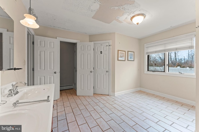 bathroom with a textured ceiling, a baseboard heating unit, and sink