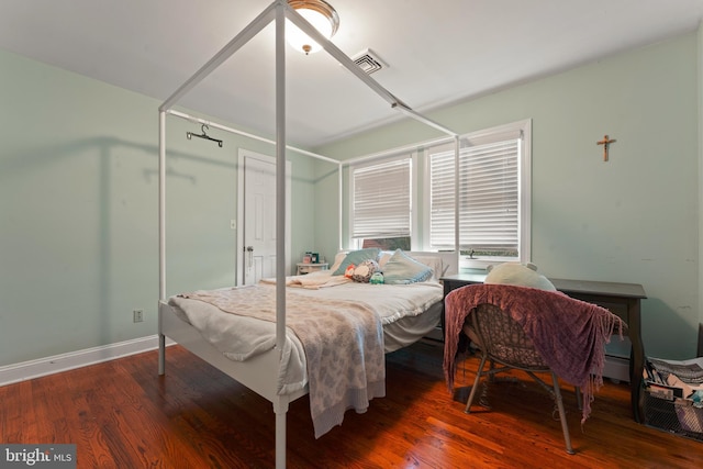 bedroom with hardwood / wood-style floors and baseboard heating