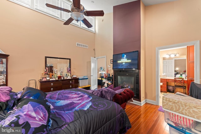 bedroom with a high ceiling, light hardwood / wood-style flooring, ensuite bath, and ceiling fan