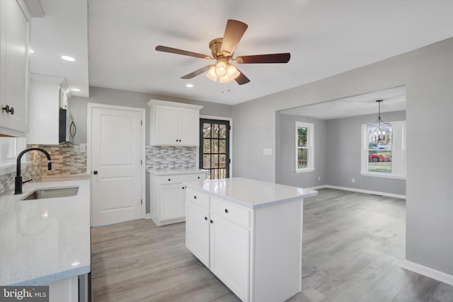 kitchen featuring white cabinets, decorative backsplash, a center island, and light hardwood / wood-style flooring