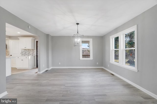 unfurnished dining area featuring a notable chandelier and light hardwood / wood-style flooring