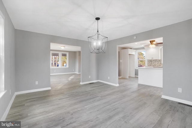 interior space featuring ceiling fan with notable chandelier and light hardwood / wood-style floors