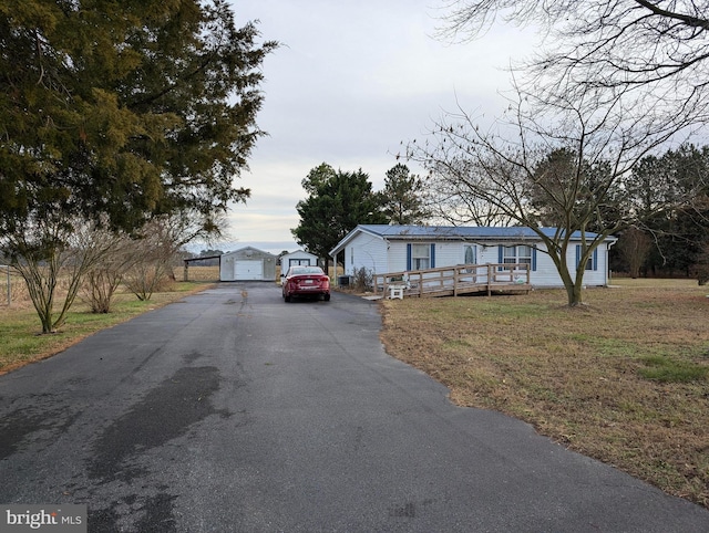 view of front of property featuring a front yard, a deck, a garage, and an outdoor structure