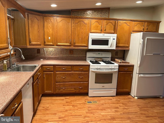 kitchen featuring light wood-type flooring, white appliances, backsplash, and sink