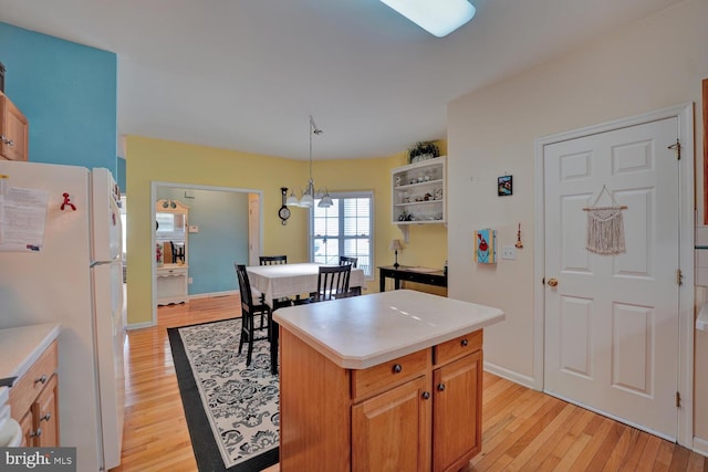 kitchen with a center island, hanging light fixtures, light hardwood / wood-style floors, white fridge, and a chandelier